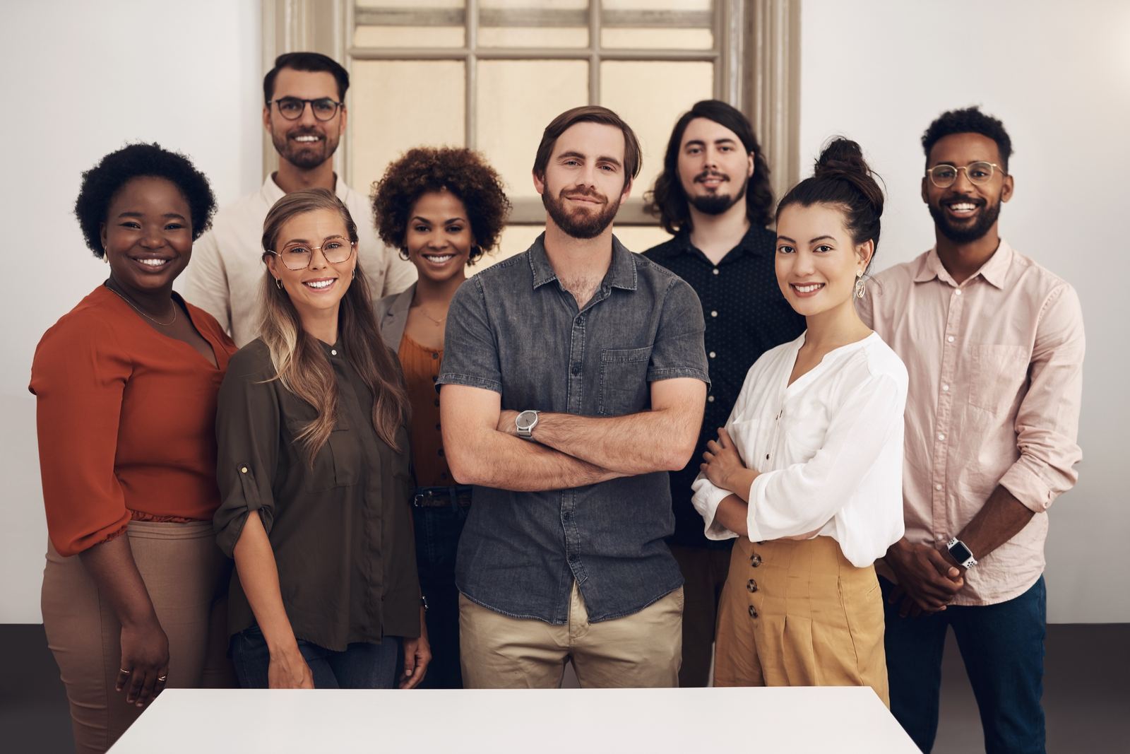 A diverse group of colleagues stood together smiling in a modern office